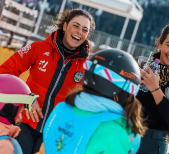 Maestra della Scuola Sci 5 Laghi sorride con i bambini del corso